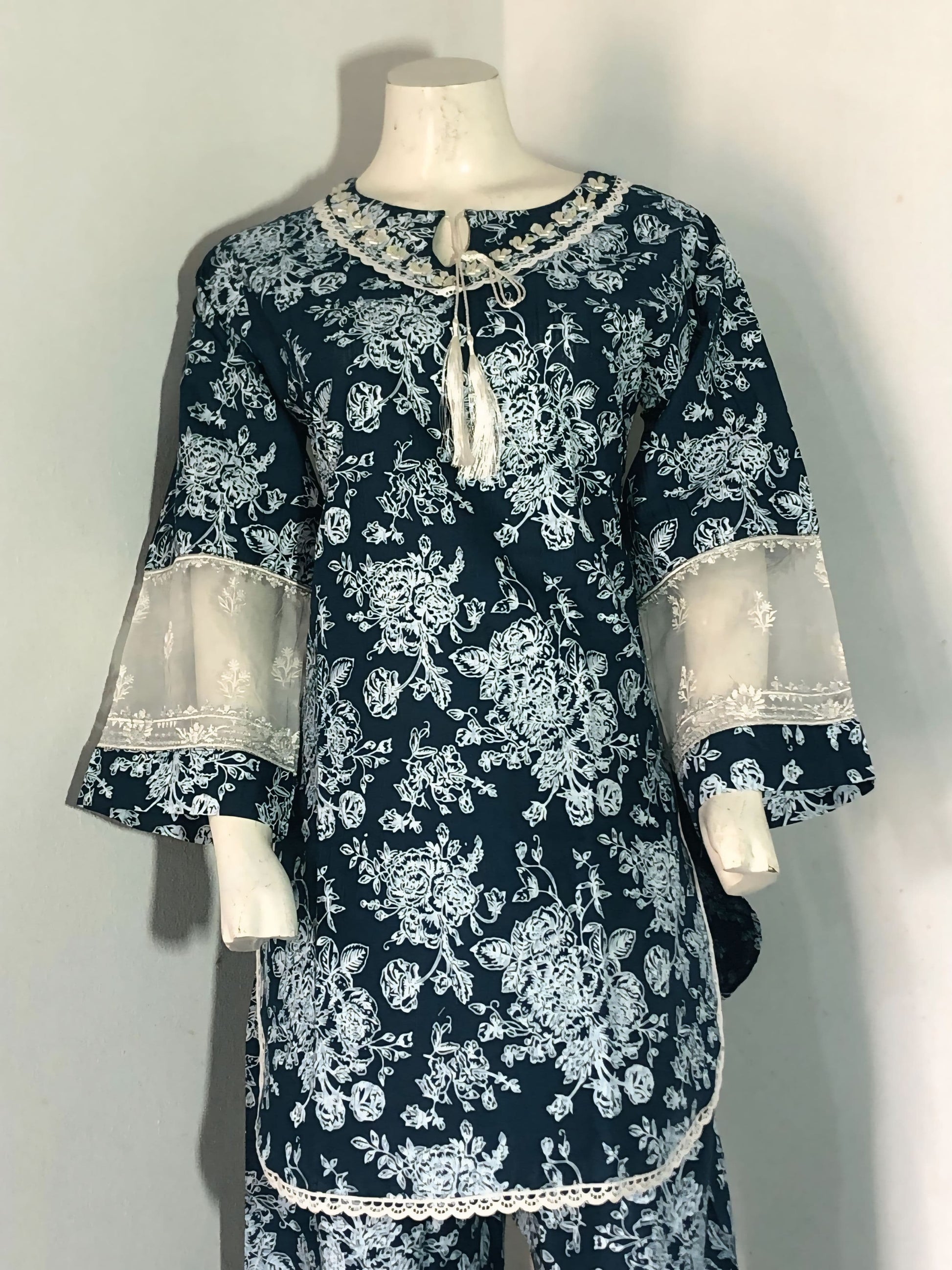 Navy blue floral dress with white lace details on a mannequin against a plain background